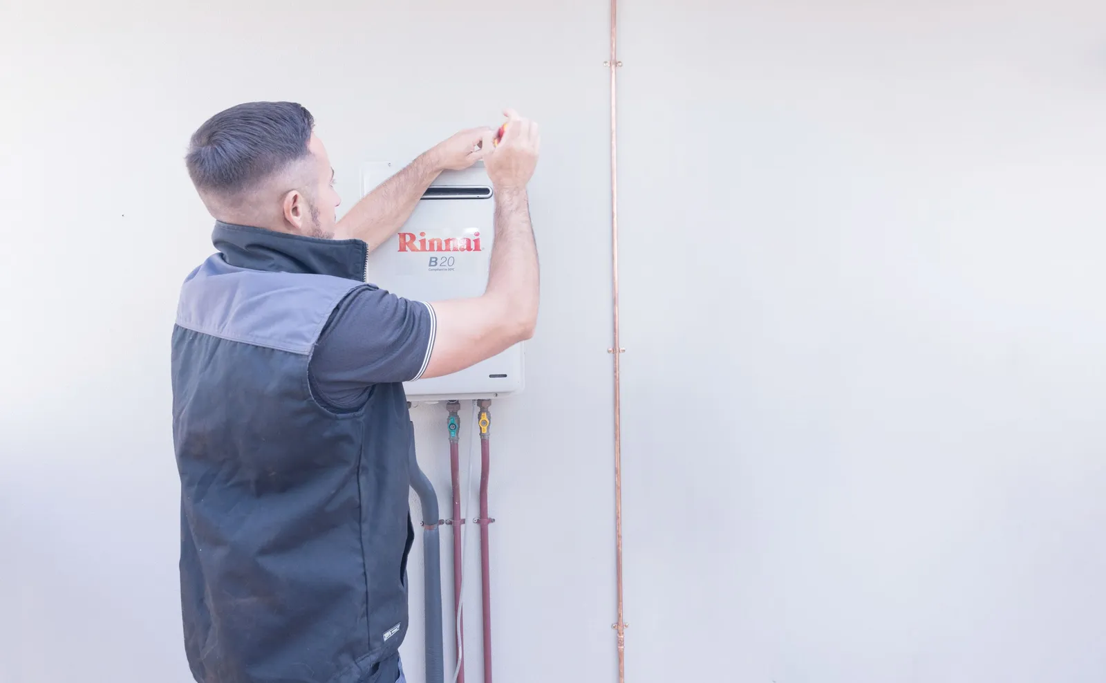 A Sureflow plumber setting up a wall-mounted hot water unit.